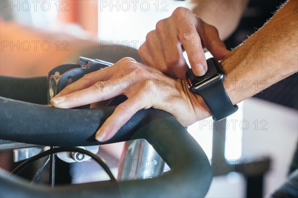 Caucasian woman tapping smart watch on stationary bicycle