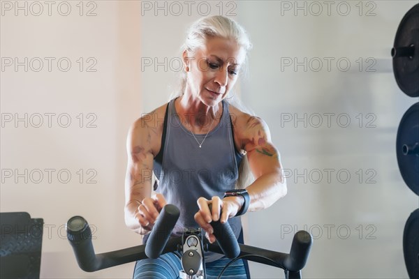 Caucasian woman riding stationary bicycle checking smart watch