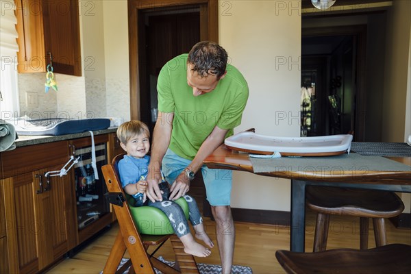 Father buckling son into highchair