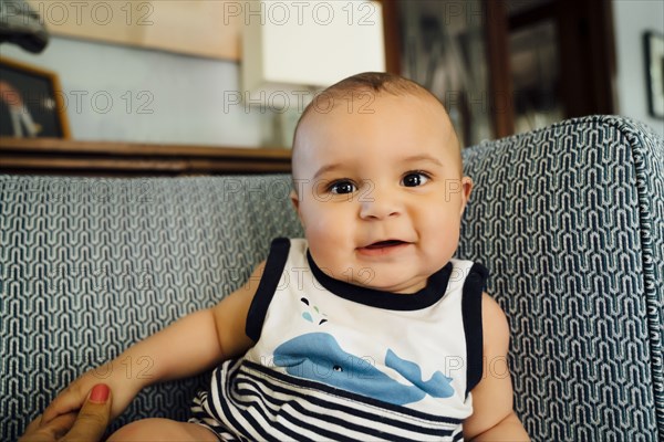 Portrait of smiling Mixed Race baby boy on chair