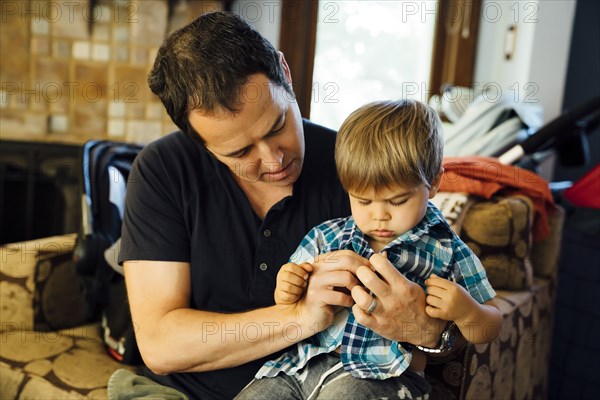 Father buttoning shirt for son