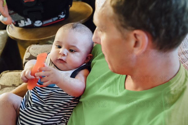 Father holding baby son playing with toy