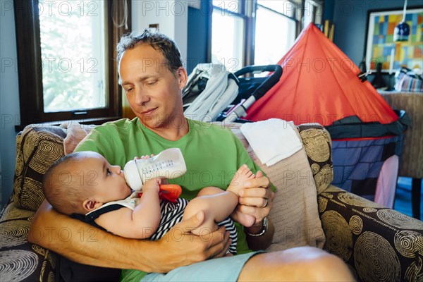 Father holding baby son drinking milk from bottle