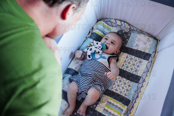 Father watching baby son in crib