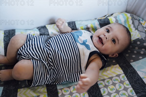 Smiling Mixed Race baby boy laying in crib