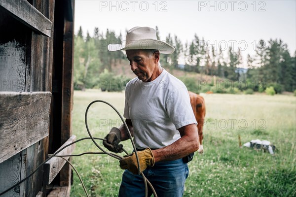 Caucasian farmer tying rope on fence