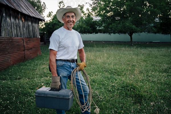 Caucasian farmer carrying rope and toolbox