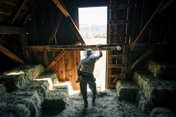 Caucasian farmer resting in barn near bales of hay