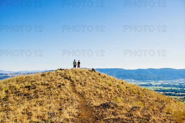 Distant Caucasian couple standing on hill holding hands