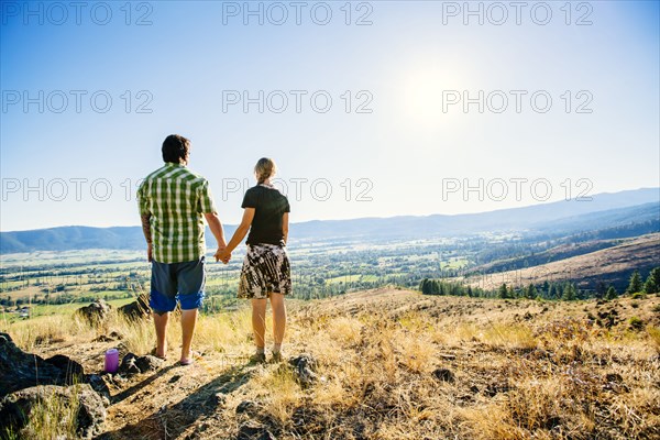 Caucasian couple standing on hill holding hands