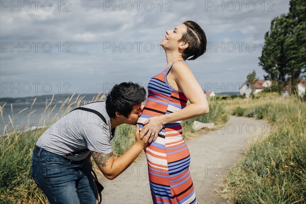 Woman kissing belly of expectant mother