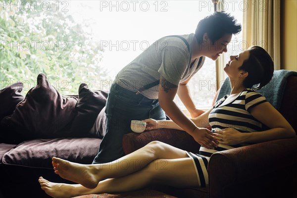 Pregnant lesbian couple kissing in livingroom