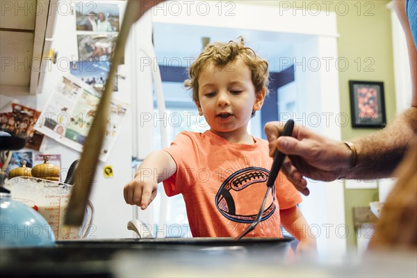 Caucasian father and son cooking on stove