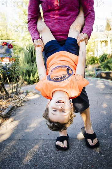Caucasian mother holding son upside-down
