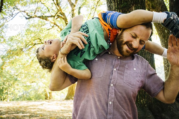 Caucasian father playing with son on shoulder