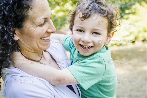 Caucasian mother carrying smiling son