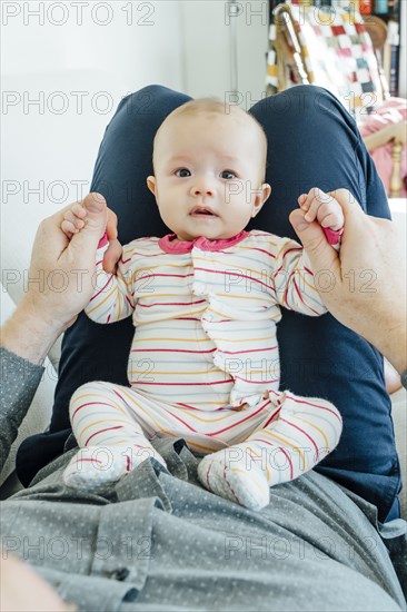 Father playing with baby daughter in lap