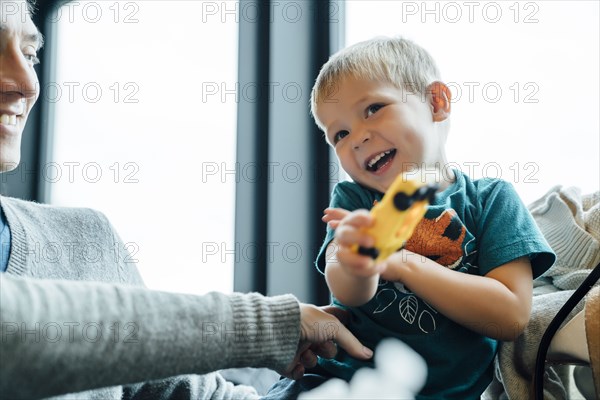 Arm of mother tickling son holding toy car