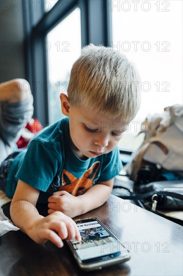 Mixed Race boy laying on table using cell phone