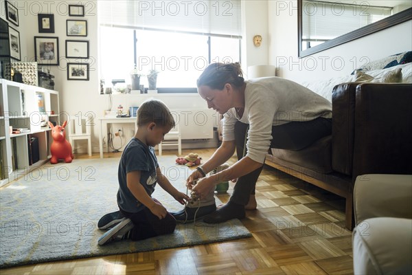 Mother teaching son to tie shoelace