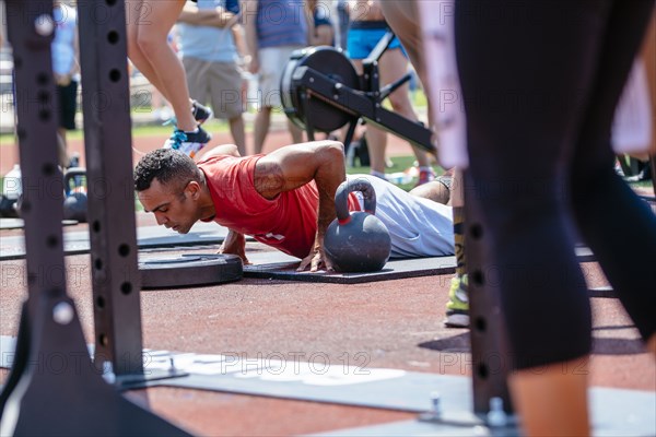 Man doing push-ups near kettlebell outdoors