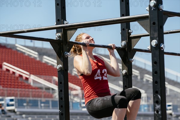 Caucasian woman doing chin-ups outdoors