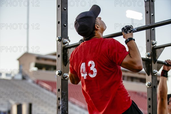 Caucasian man doing chin-ups outdoors