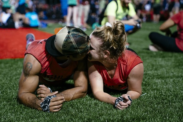 Man and woman laying on artificial turf and kissing