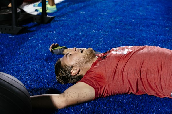 Fatigued Caucasian man laying on sports field