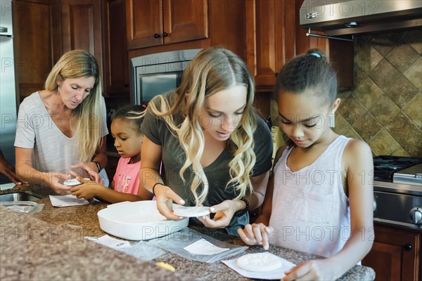 Mother and daughters cooking in domestic kitchen