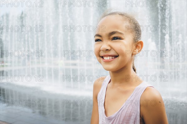 Smiling Mixed Race girl near fountain
