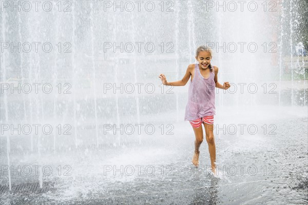 Smiling Mixed Race girl running fountain