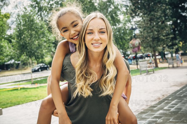 Smiling woman carrying sister piggyback