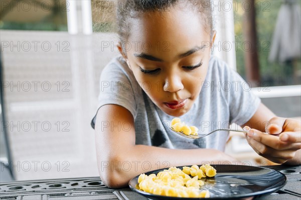 Mixed Race girl eating food with fork