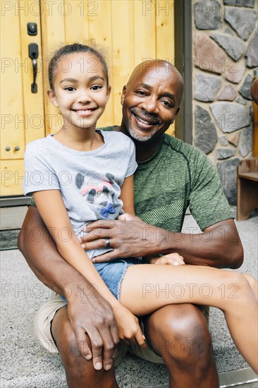 Portrait of girl sitting in lap of father