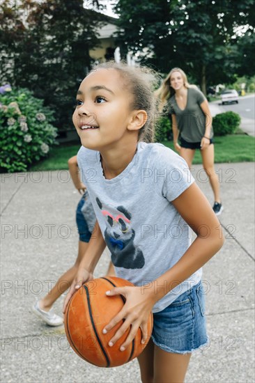 Mother and daughters playing basketball in driveway