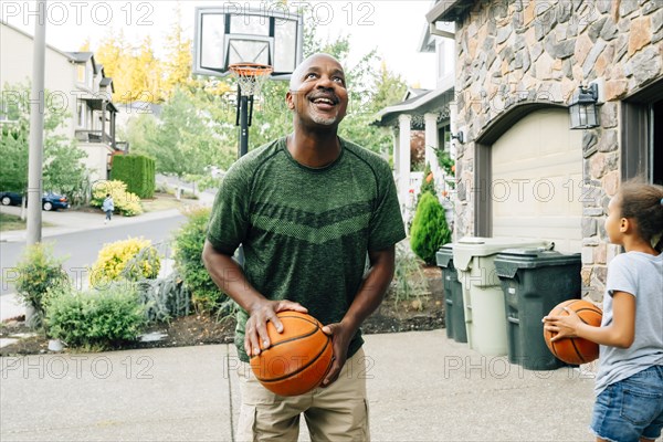 Father and daughter playing basketball in driveway