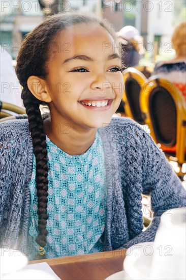 Smiling Mixed Race girl sitting at restaurant table