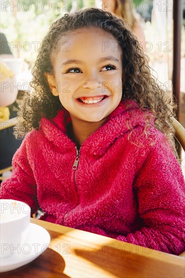 Smiling Mixed Race girl sitting at restaurant table
