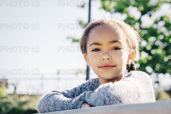 Confident Mixed Race girl leaning on wooden railing