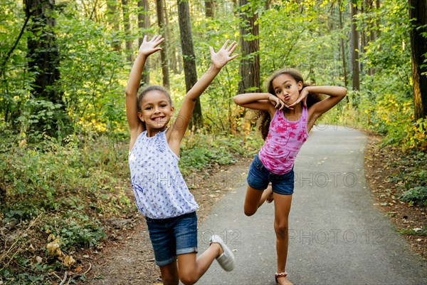 Mixed Race sisters having fun posing on forest path