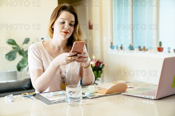 Woman sitting at table texting on cell phone