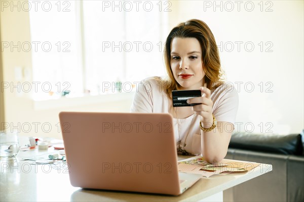 Woman sitting at counter online shopping with laptop