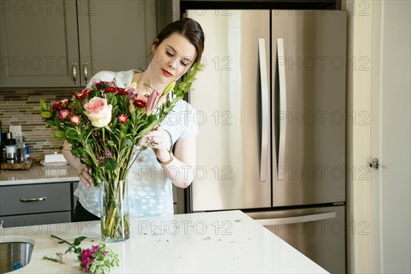 Woman arranging flowers in domestic kitchen