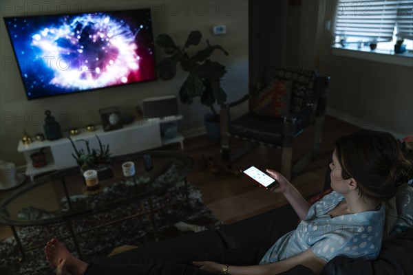 Woman watching television and using cell phone