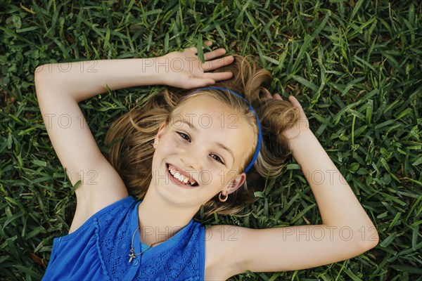 Close up portrait of smiling Caucasian girl laying on grass