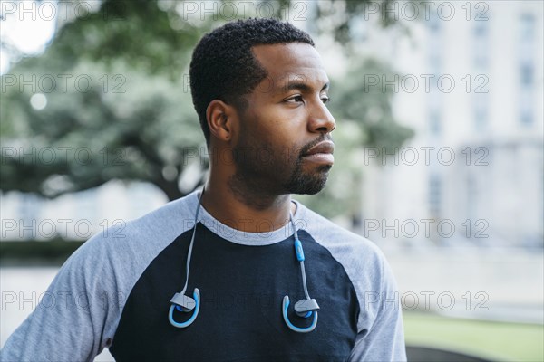 Serious Black man with earbuds looking away