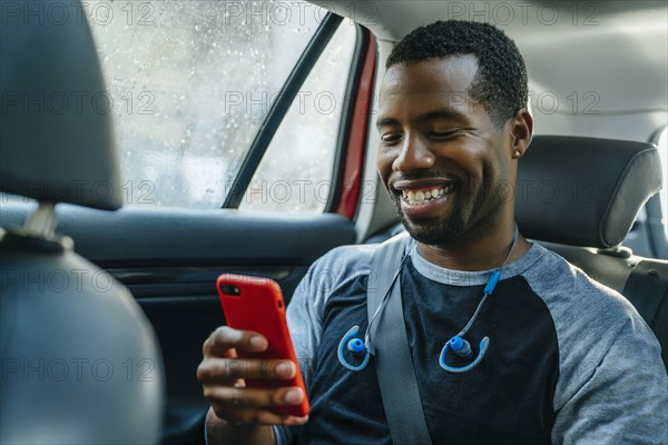 Smiling Black man texting on cell phone in car