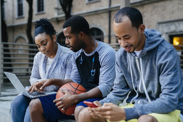 Black friends using laptop and cell phone