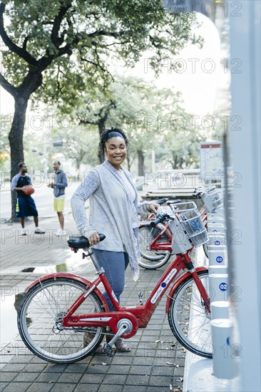 Black woman posing with rental bicycle